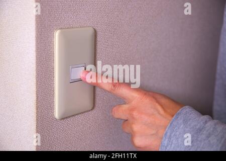 Light switch pushing by male hand daytime closeup Stock Photo