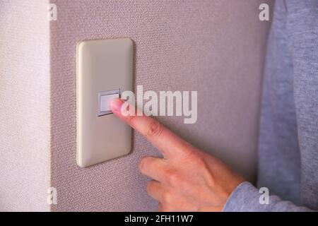 Light switch pushing by male hand daytime closeup Stock Photo