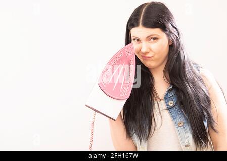 young attractive woman or housewife sad bored and stressed holding dirty fired iron angry and frustrated in domestic work housekeeping and housework c Stock Photo