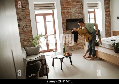 Happy young couple is dancing and showing their feelings in new flat. Lovely family moving to new apartment Stock Photo