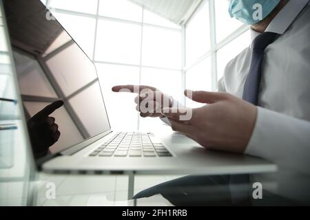 Concentrated young male professional wearing breath protective mask, working on computer after washing hands with antiseptic liquid, preventing Stock Photo