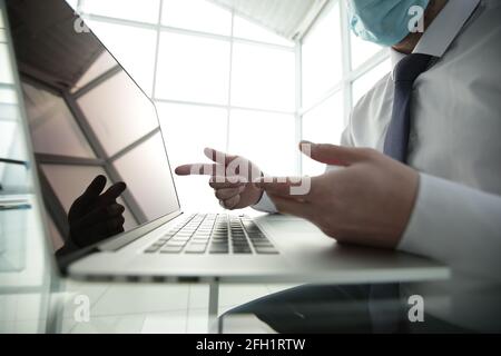 Concentrated young male professional wearing breath protective mask, working on computer after washing hands with antiseptic liquid, preventing Stock Photo