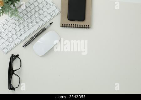 White keyboard mouse glasses pen notepad phone flower in pot on white background Stock Photo