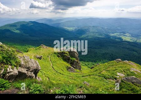 view from pikui mountain. huge stones on the grassy slopes. summer landscape of carpathian mountains. borzhava ridge in the distancee beneath a sky wi Stock Photo