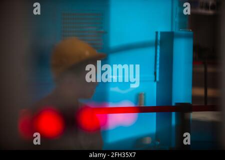 Moinak hydroelectric power station. Abstract industrial background. Blurred blue panel with red lamps, and blurred worker in yellow hardhat. Stock Photo