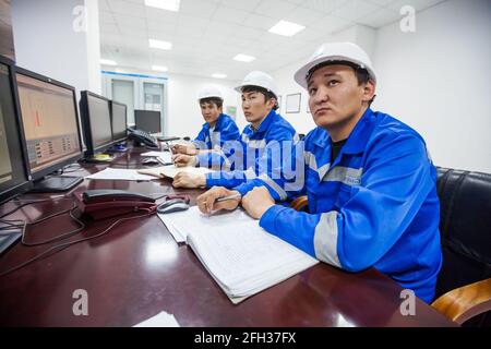 Moinak hydroelectric power station, control room. Three Asian operators supervising processes. Right man in focus. Stock Photo