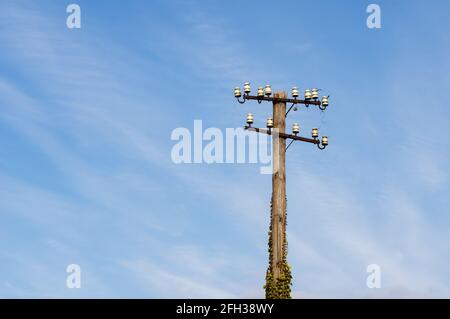 low angle view of old and decaying telegraphy pole at a train station in Germany against blue sky with cirrus clouds. Selective focus on foreground. Stock Photo