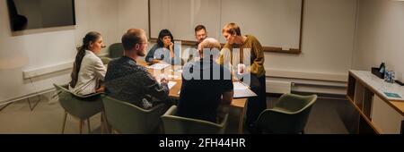 Wide angle shot of people having meeting inside office conference room. Group of corporate professionals planning new project in boardroom. Stock Photo