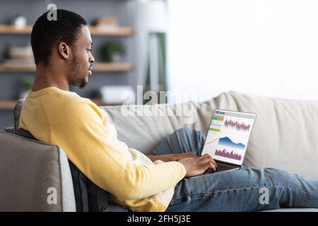Concentrated black guy trading on market online, using laptop Stock Photo