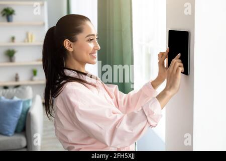 Woman using smart wall home control system Stock Photo