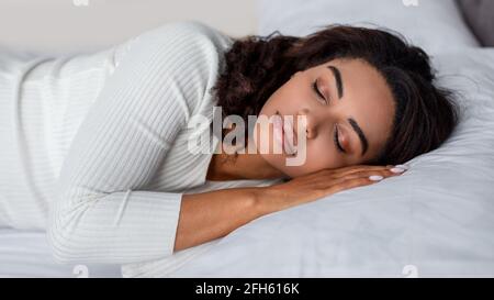 Portrait of young African American woman sleeping in bed Stock Photo
