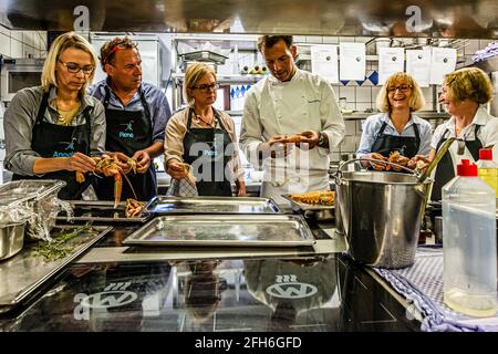 Michelin-starred chef Thomas Kellermann leads a cooking class in the kitchen of Wernberg Castle, Wernberg-Köblitz, Upper Palatinate, Germany. Together with participants journalist Angela Berg (left in frame), René and Petra, he prepares langostinos – his signature dish, brought from his time at the restaurant Vitrum in Berlin. Kellermann headed the kitchen at Wernberg Castle until May 2018 and earned the second Michelin star in 2011. Stock Photo