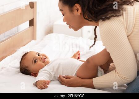 African Mommy Waking Up Baby After Daytime Sleep In Bedroom Stock Photo