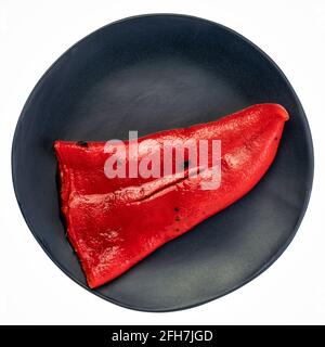 red roasted pepper on an isolated black ceramic plate Stock Photo