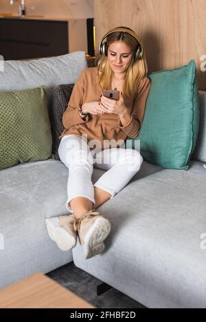 Crop anonymous female with delicious cooked broccoli on fork browsing internet on netbook at table Stock Photo