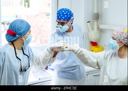 Male surgeon with female coworkers in uniforms greeting each other with high five at work in hospital Stock Photo