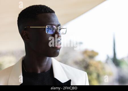 Young confident black male entrepreneur with stylish jacket looking at camera standing in the city Stock Photo