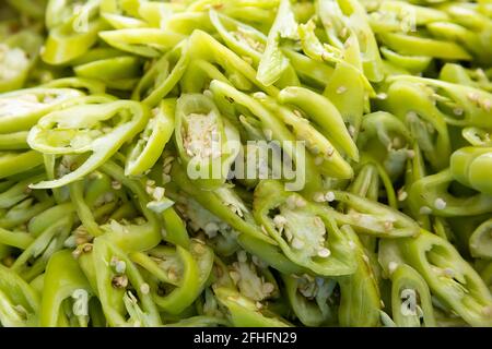 Sliced or chopped green color Thai capsicum annuum linn var acuminatum fingerh, hot pepper chilli ready to cook, vegetable background Stock Photo