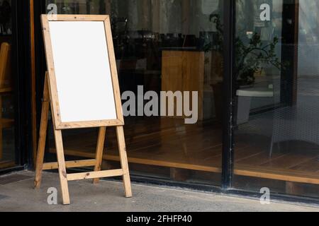 Old whiteboard stand in front of restaurant or cafe, empty for advertising display Stock Photo