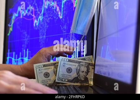 Disposable face mask on blurred background of computer screen and monitor with stock chart Stock Photo
