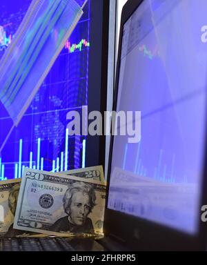 Disposable face mask on blurred background of computer screen and monitor with stock chart Stock Photo