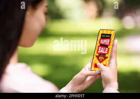 Unrecognizable asian woman holding mobile phone with sale advert Stock Photo