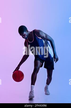 Full body portrait of a black basketball player sits on a floor and ...