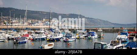 Panoramic view of Lyme Regis beach seen through yachts and boats moored in The Cobb harbour in Lyme Regis, Dorset, UK on 21 April 2021 Stock Photo