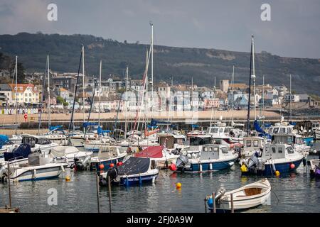 Lyme Regis beach seen through yachts and boats moored in The Cobb harbour in Lyme Regis, Dorset, UK on 21 April 2021 Stock Photo