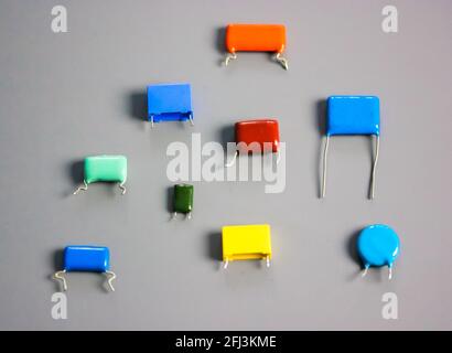 Subminiature polypropylene multicolored film capacitors on gray background flatly. Vintage electronic parts. Resistors and capacitors different size a Stock Photo