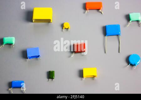 Subminiature polypropylene multicolored film capacitors on gray background flatly. Vintage electronic parts. Resistors and capacitors different size a Stock Photo
