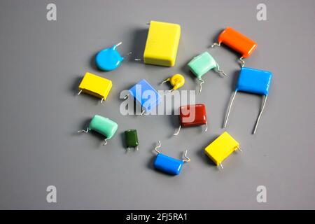 Subminiature polypropylene multicolored film capacitors on gray background flatly. Vintage electronic parts. Resistors and capacitors different size a Stock Photo