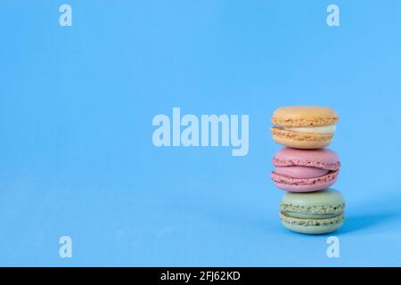 Three Macaroons, yellow, pink and green on green background Stock Photo