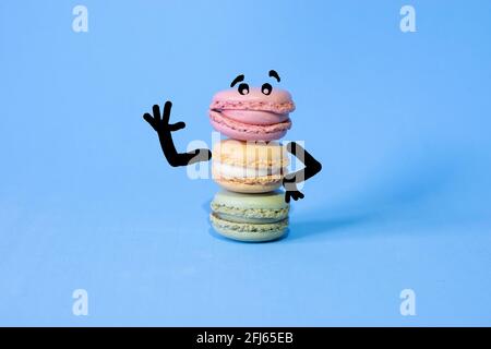 Waving cartoon drawn on coloured macarons on a blue background Stock Photo