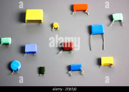 Subminiature polypropylene multicolored film capacitors on gray background flatly. Vintage electronic parts. Resistors and capacitors different size a Stock Photo