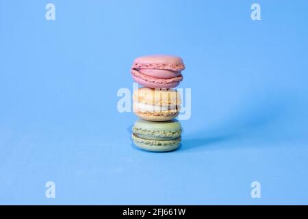 three coloured macarons on a blue background Stock Photo