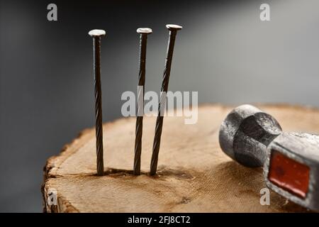 Screw nails and hammer on stump, grey background Stock Photo