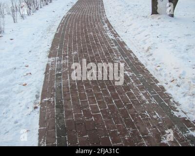 A tiled path in a snow-covered park Stock Photo