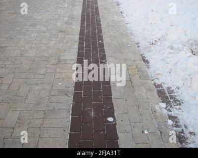 A tiled path in a snow-covered park Stock Photo