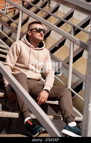 A young man sits on the steps in the city. Urban style. Lifestyle photo Stock Photo