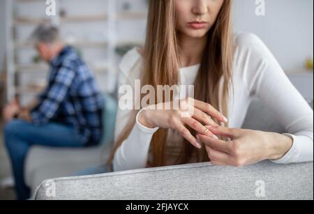 Cropped view of middle-aged woman taking off wedding ring, thinking about breakup with her husband at home, copy space Stock Photo