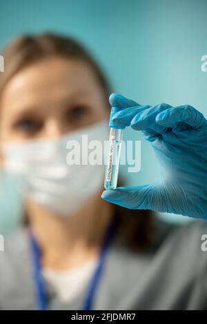 Close-up of female nurse in blue glove holding test tube of coronavirus vaccine while preparing for vaccination Stock Photo