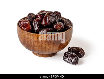 Sweet dried dates in a wooden bowl isolated on white background. Delicious vegetarian, dieting and high-calorie healthy food ingredient. Ready to eat Stock Photo