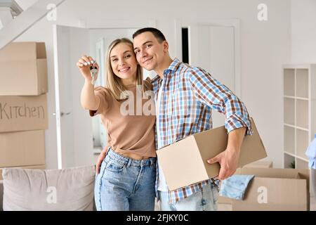 Happy young couple first time home owners holding keys in new home. Stock Photo