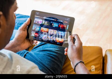Adult Asian male age 35 watching / browsing videos in iPad from on demand video player app Stock Photo