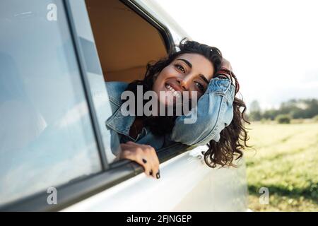 Attractive young woman enjoying road trip. Smiling female looks out Stock Photo