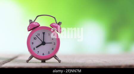 Pink Clock on the Desk at Sunrise Stock Photo