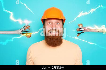 Incompetent worker electrician is unsure about his work. cyan background Stock Photo