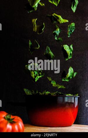 Spinach leaves falling into a pot Stock Photo