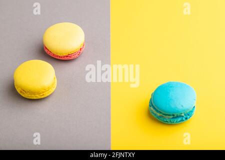 Yellow and blue macaroons on trendy gray and yellow background. side view, copy space, close up, still life. Minimalism, morning, contrast concept. Stock Photo